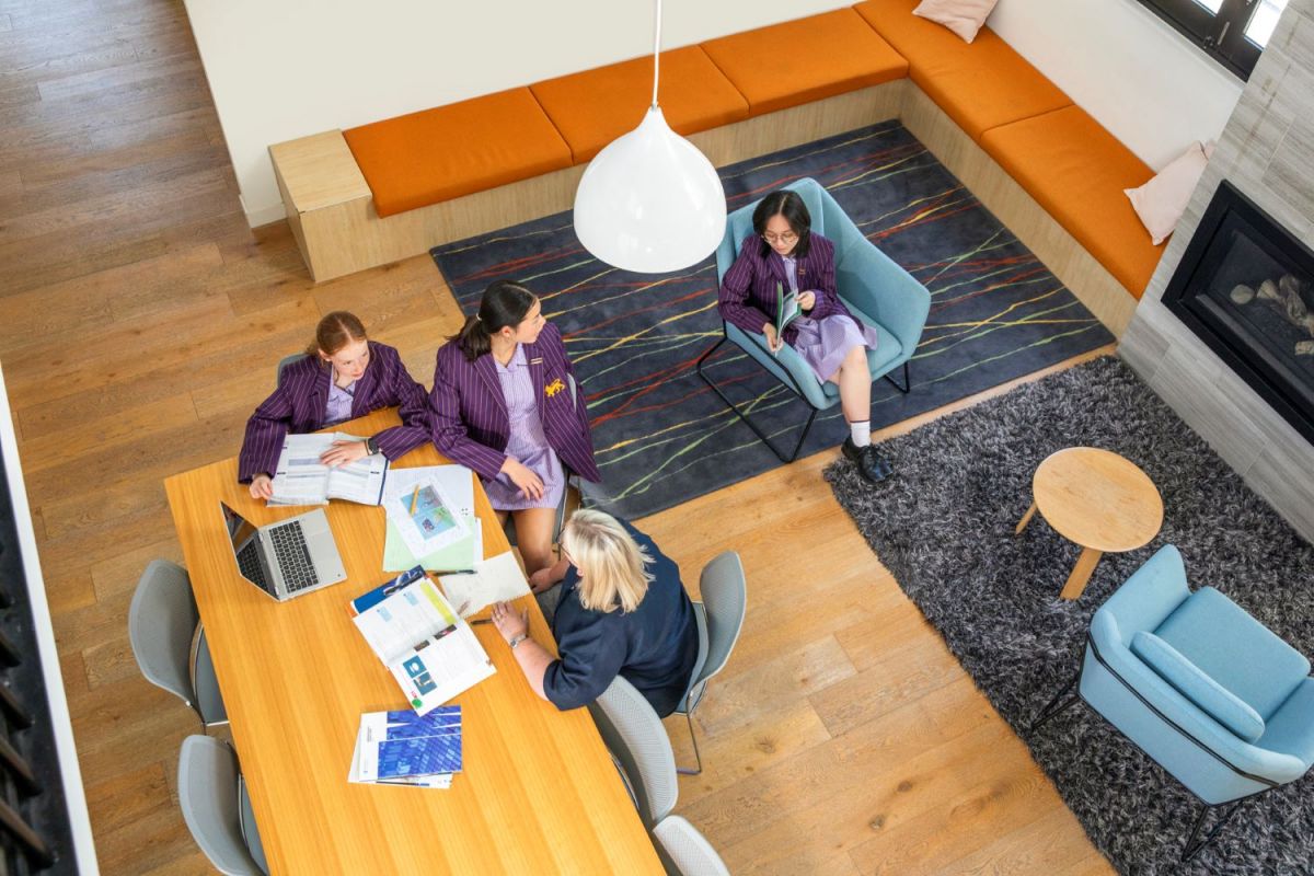 Students in a communal area with a fireplace studying and talking