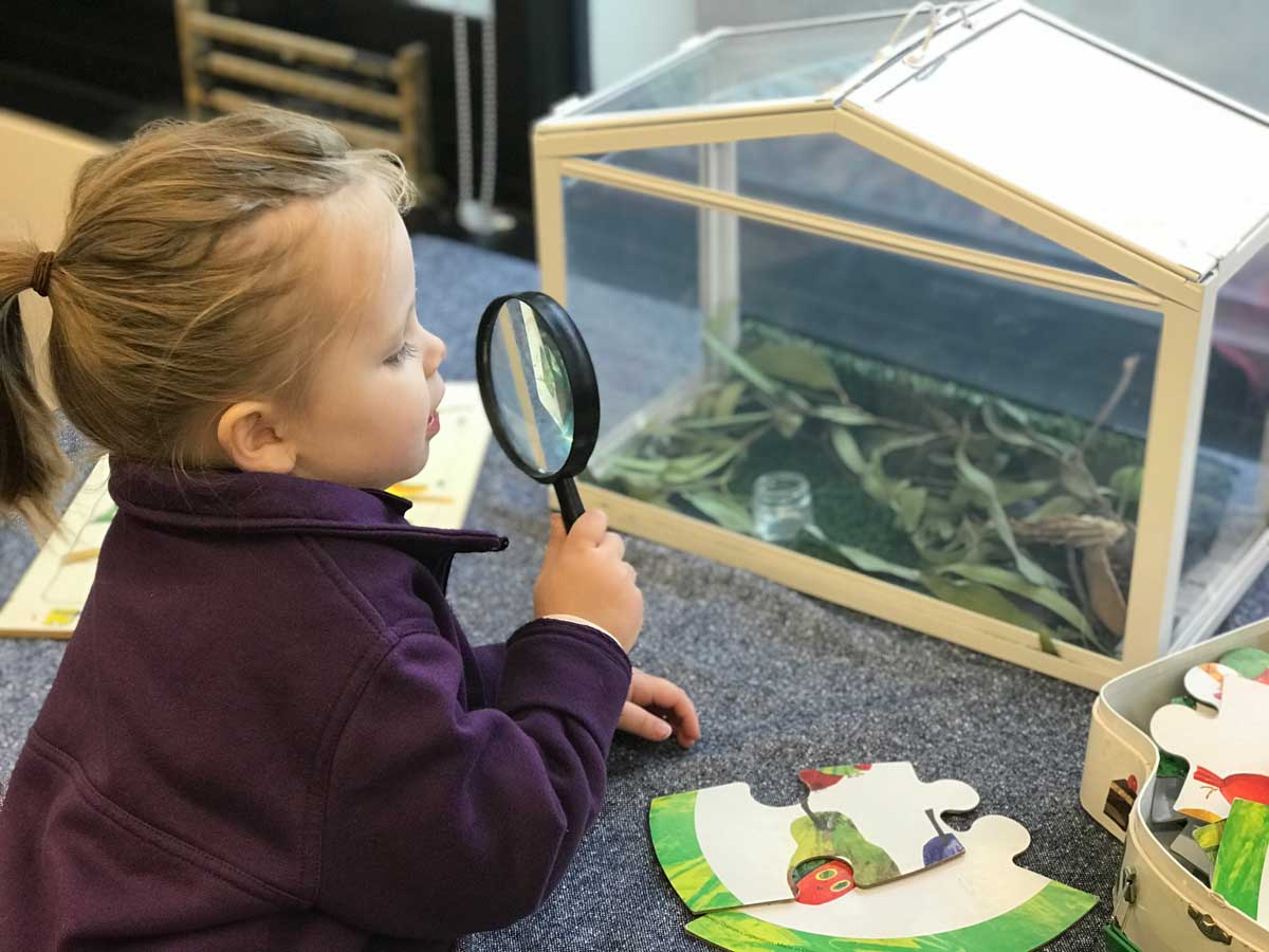 Zara, an ECLC student, uses a magnifying glass to look at casemoths