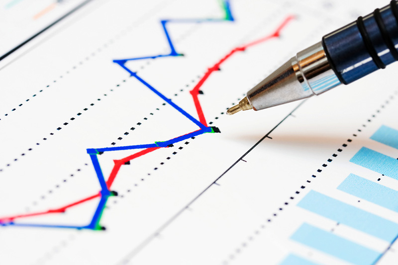 A pen hovering over paper with a printed line chart