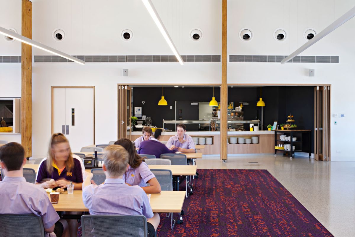 Students sitting at table eating inside a dining room