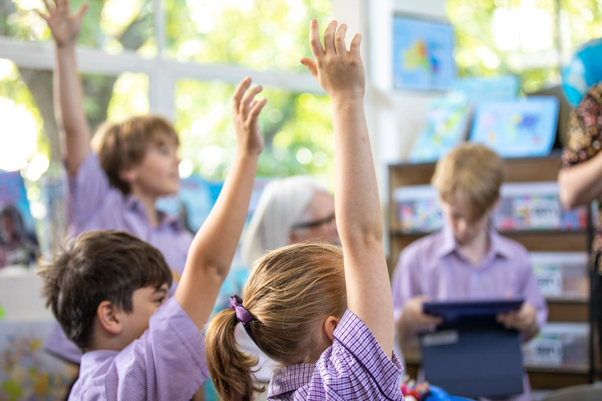 Three students hold their hands up in the air