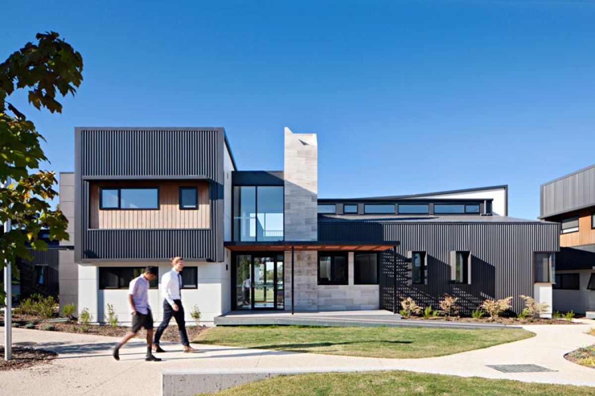 Two boys walking past the outside of a modern school boarding house