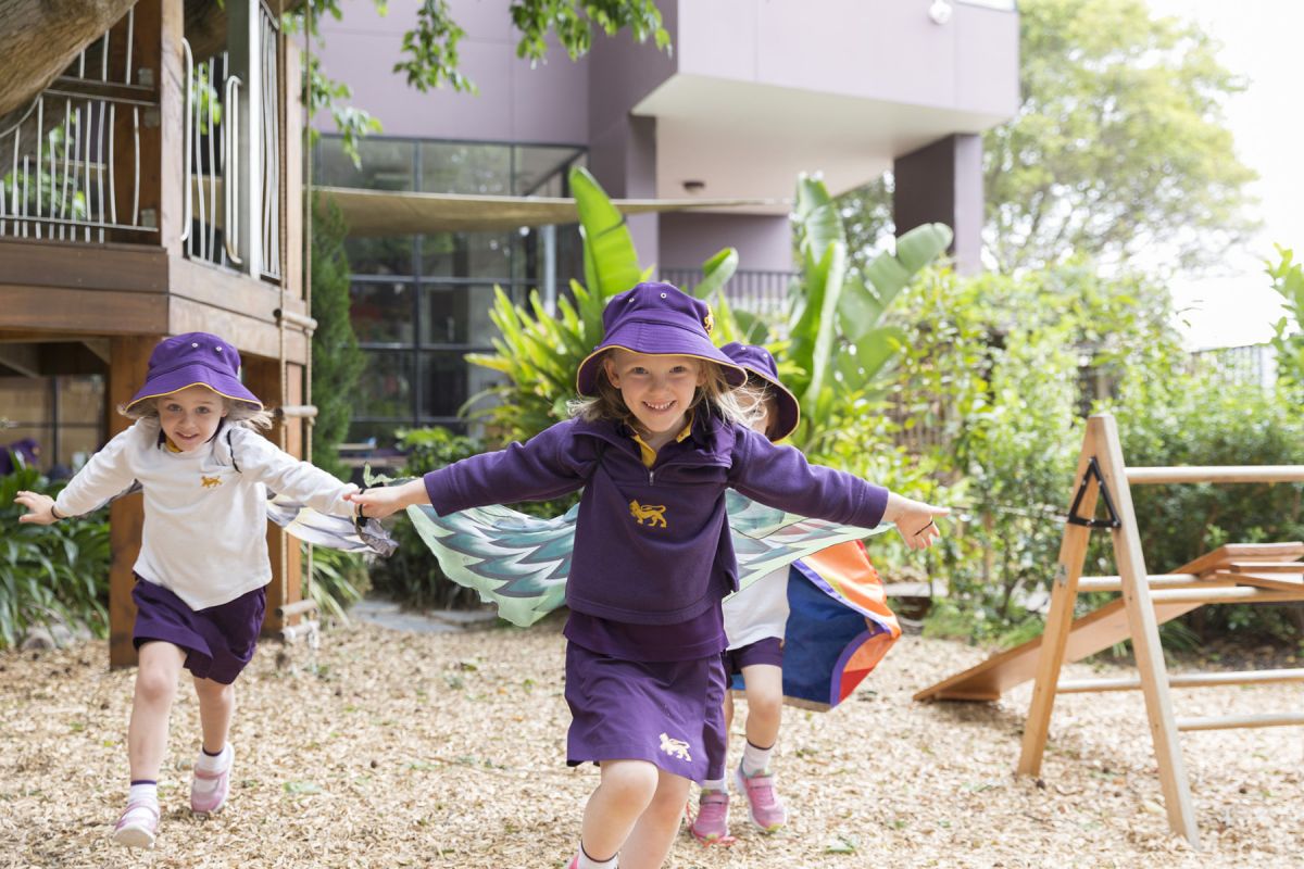 Three children with their arms out wide with capes