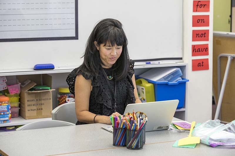 Teacher working at desk on a laptop