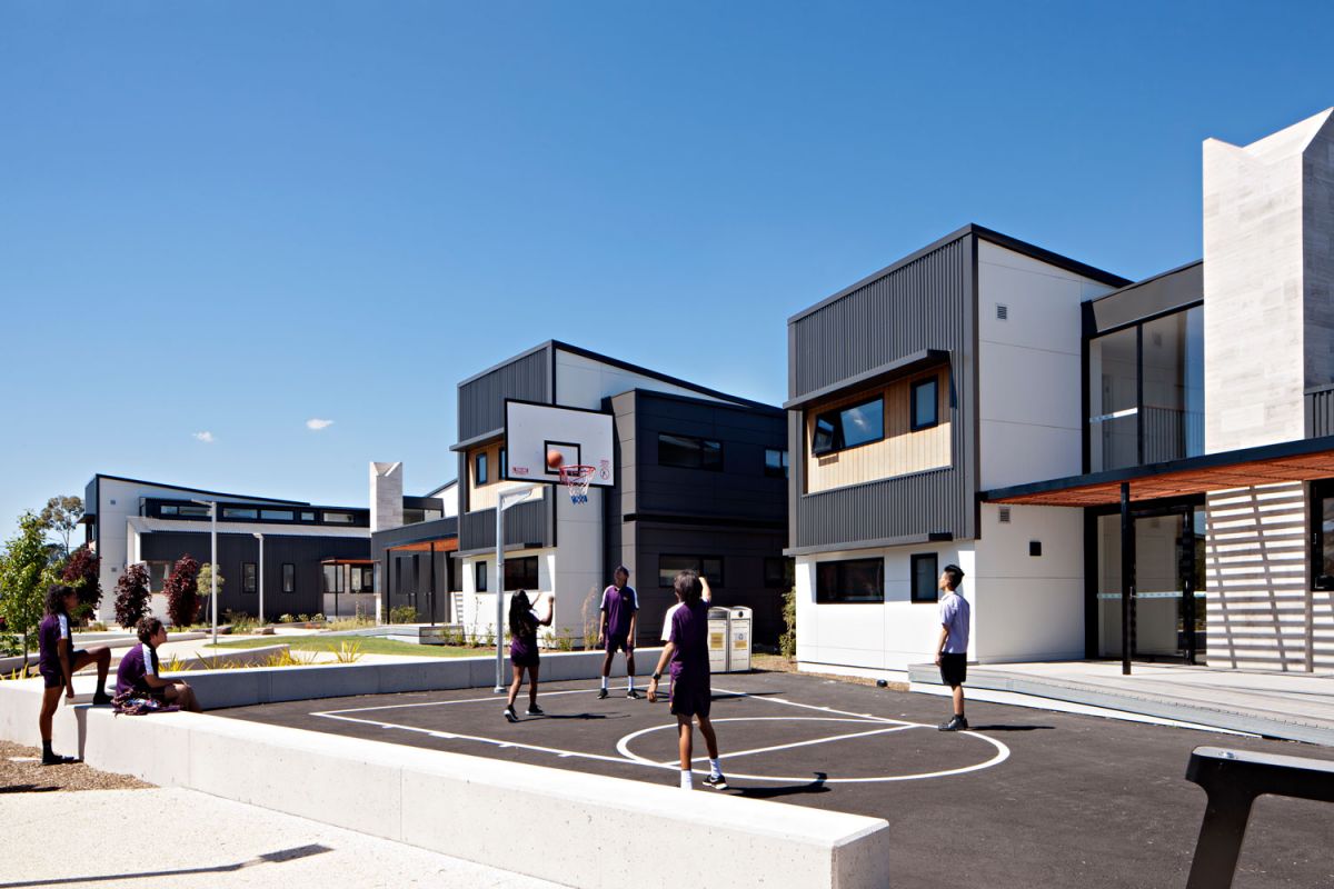 Students in sports uniform playing basketball on an outdoor court