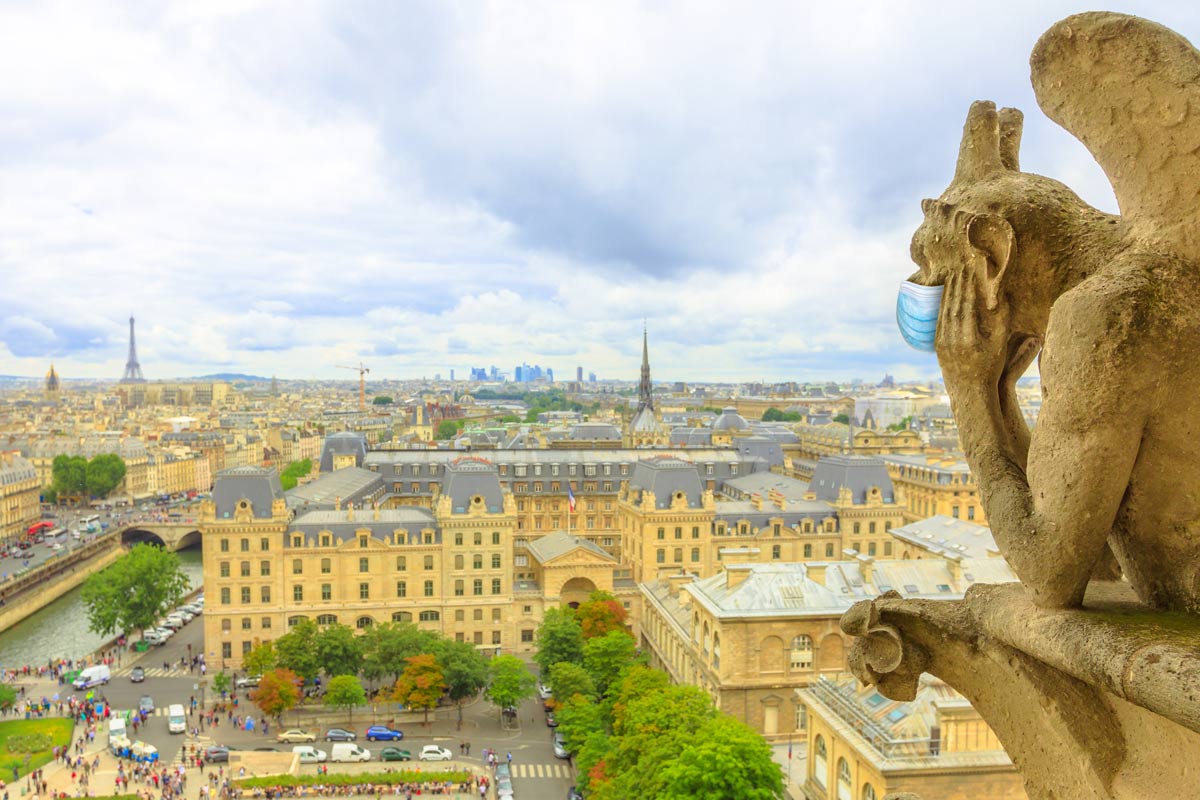 A gargoyle statue 'wears' a surgical mask as it overlooks Paris