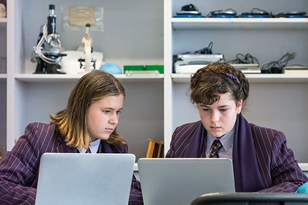 Wesley College middle school two girls studying stem on laptops in science lab 600x400