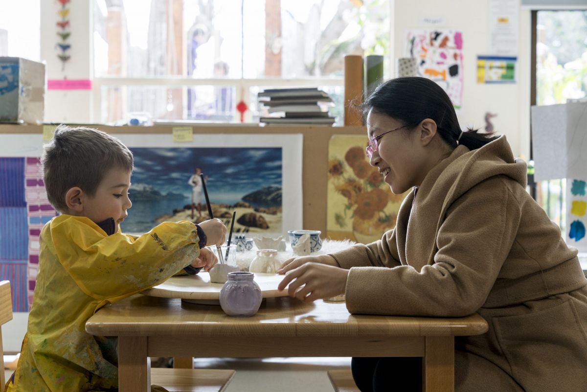 Teacher with child playing with a paint brush