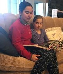 Siblings reading a book together on the couch