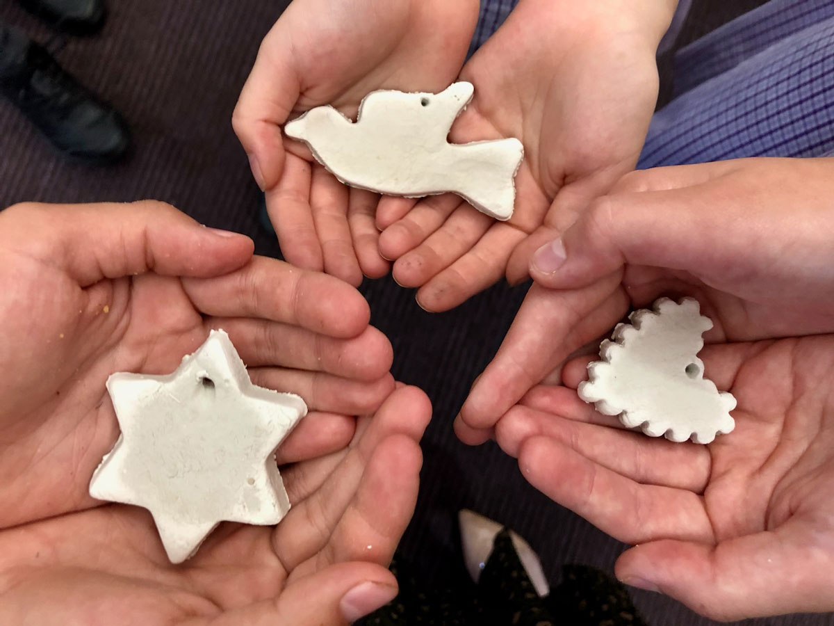 Three hands holding ceramic stars, hearts and dove sculptures