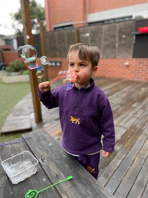 ECLC student blows bubbles through a holder
