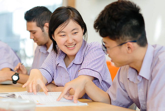 Two young Asian students studying together in a classroom