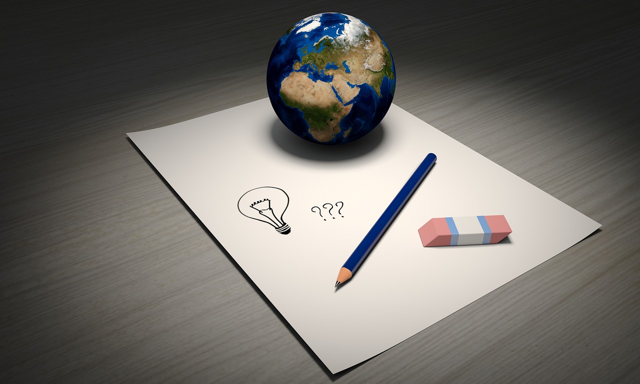 A globe, eraser and pencil on a piece of paper with a lightbulb and question mark signs