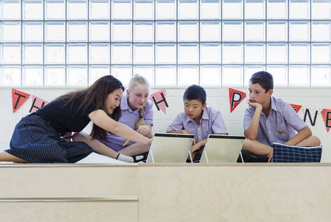 Teacher with three students sitting on the floor working on iPads