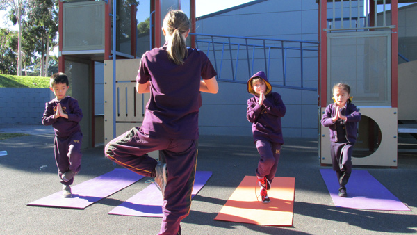 An older student teaching younger students yoga