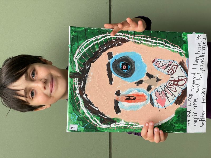 Student Ray holds up portrait he has painted