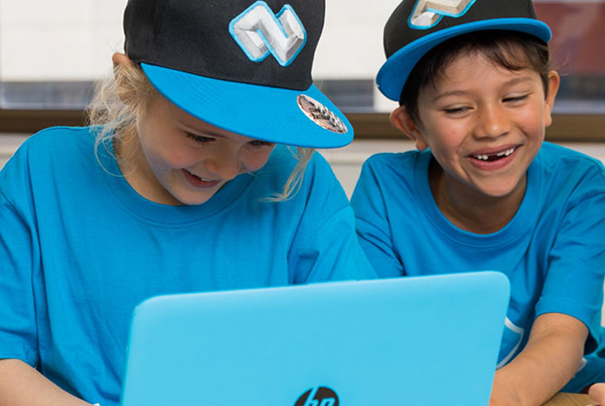 Two children laughing while looking at a laptop