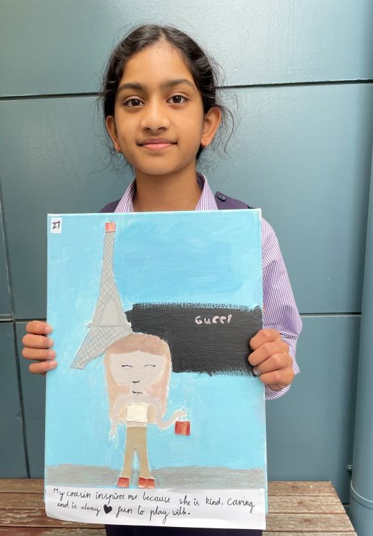 Student Nora holds up portrait she has painted
