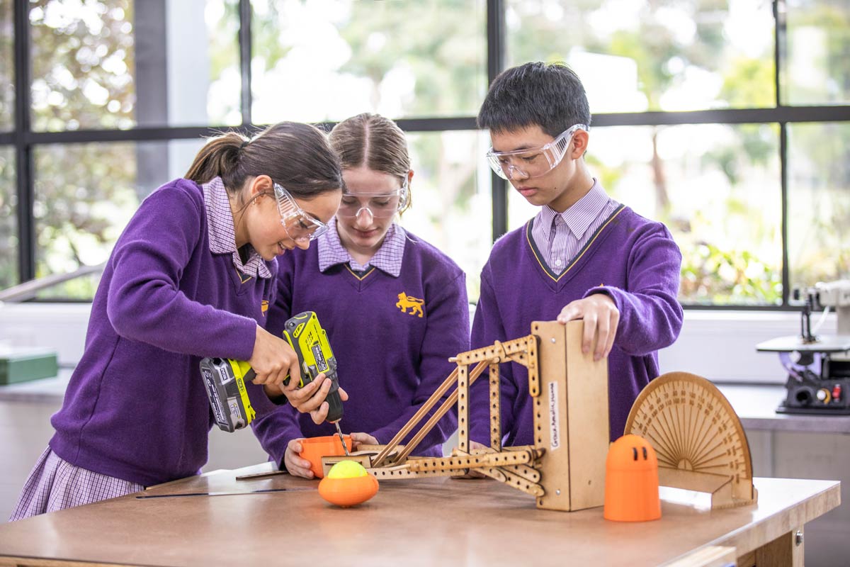 Three students build a mini catapult in the new Tech Centre