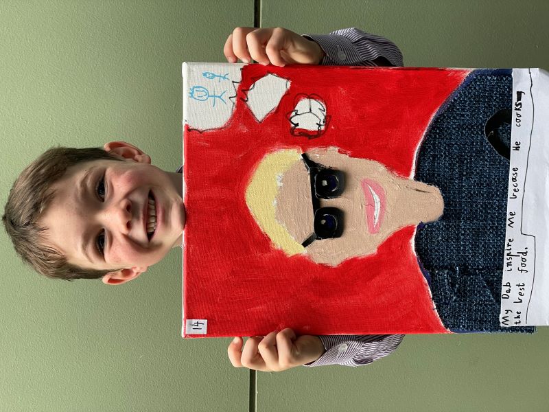 Student Felix holds up his portrait artwork