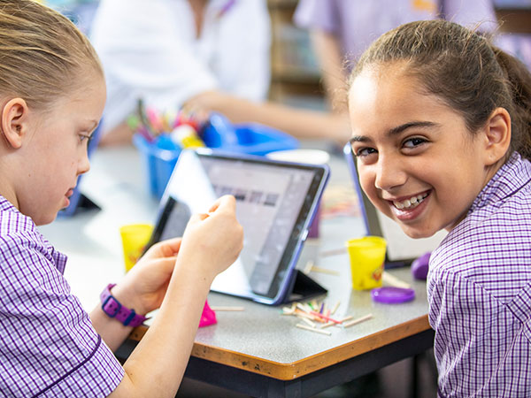 Two students cutting paper and smiling