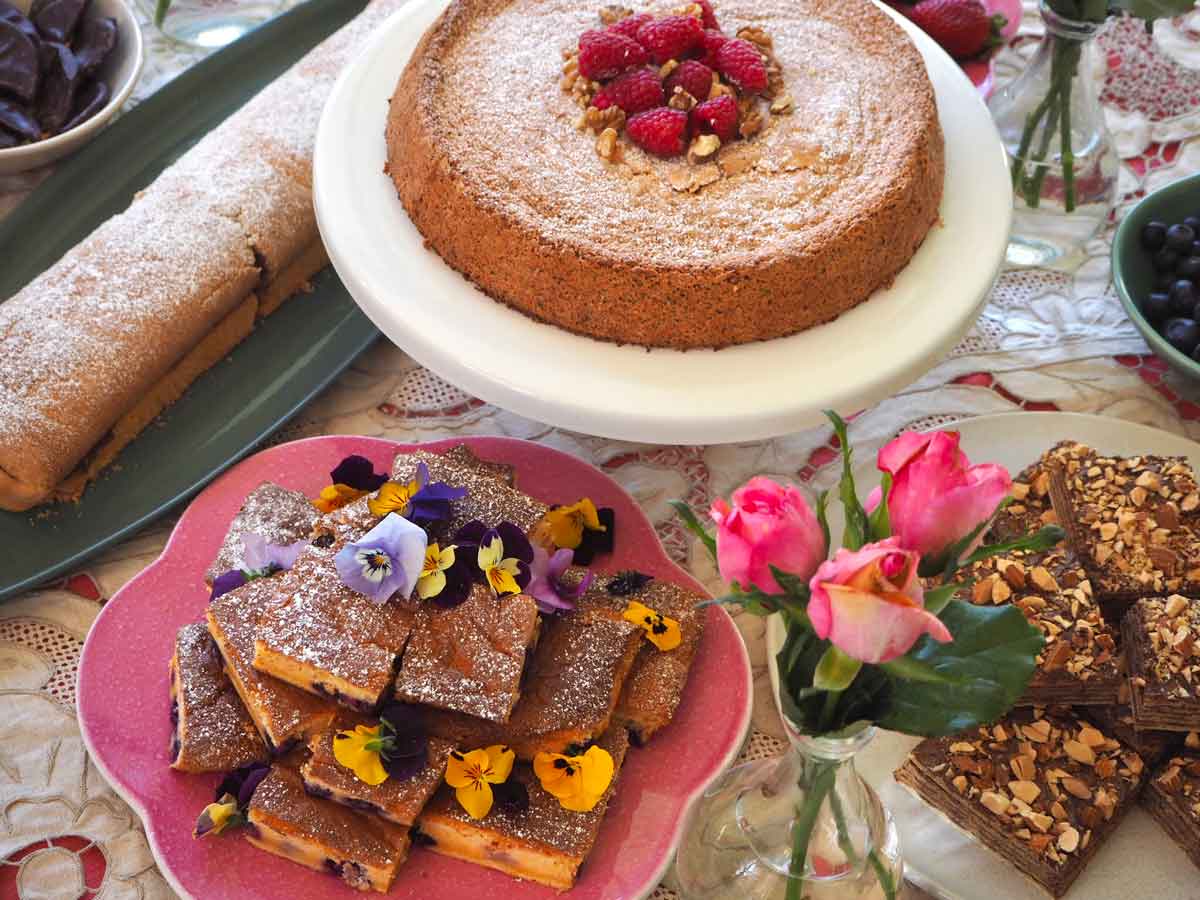 A round cake dusted with sugar and berries and two slices, baked by a student