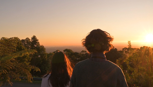 Student actors look out over the sun setting on the land