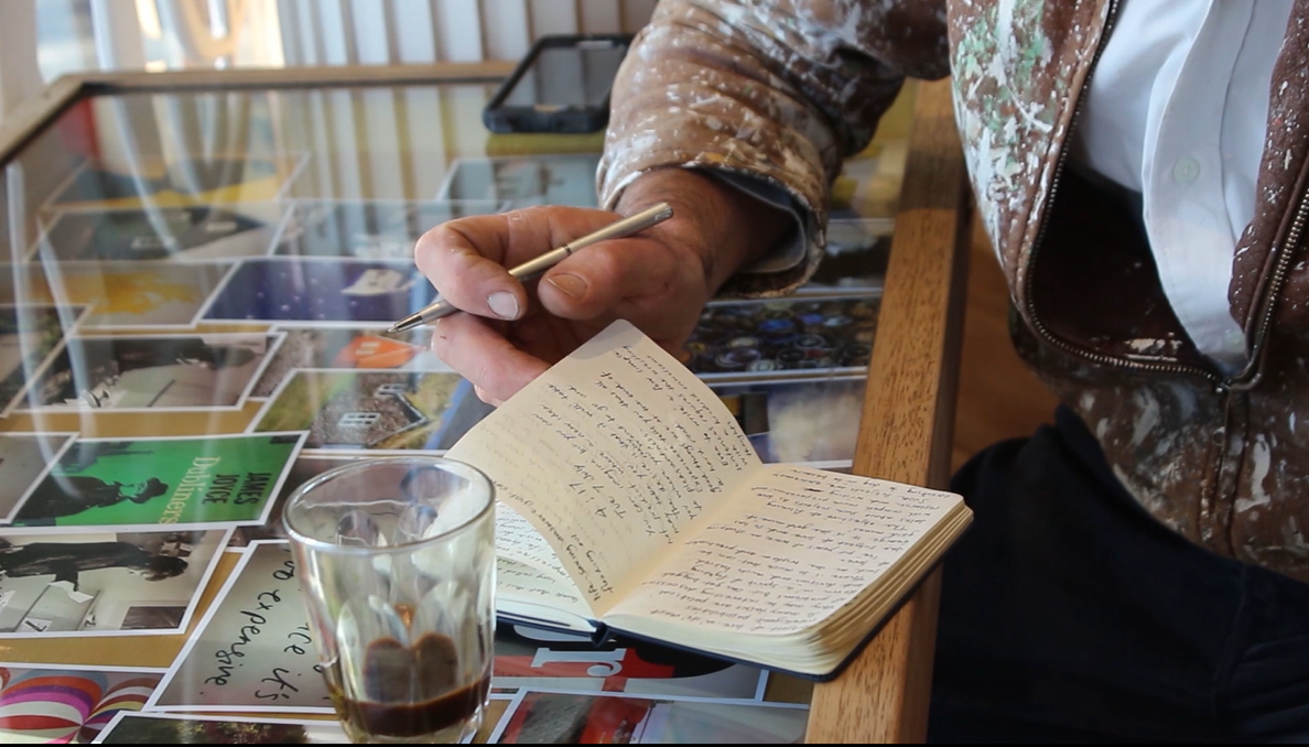 Student actor leaning on a table and writing in a book