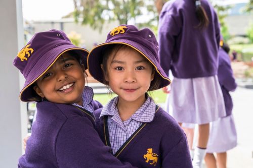Two Junior School children smiling in their Wesley hats